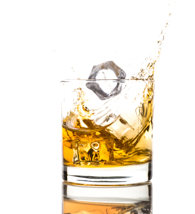 High-end beverage photograph of whiskey glass with ice and dynamic liquid splash created with precision studio lighting.